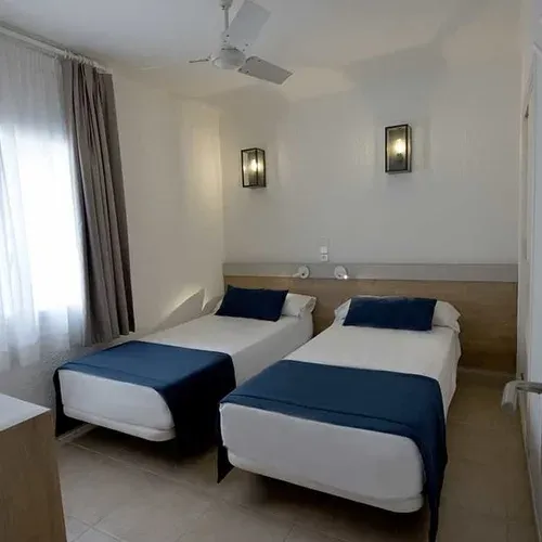 Habitació doble Estival Eldorado Resort amb llits individuals, cortines blanques i decoració moderna.
