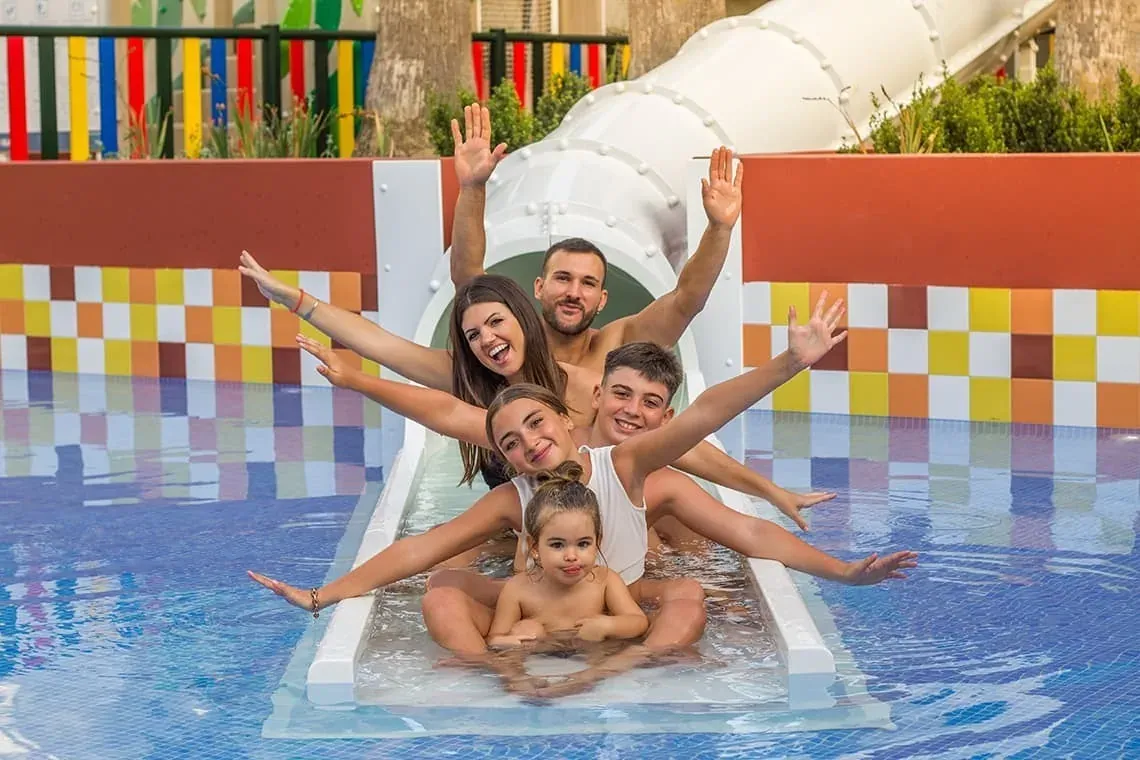 Familia feliz en tobogán de agua ESTIVAL: Corporativa. Vacaciones familiares.