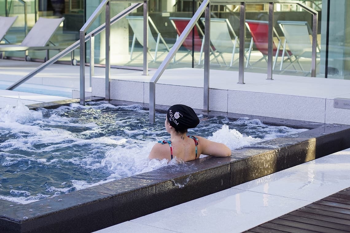 una mujer se sienta en una bañera de hidromasaje con una toalla negra con la palabra ' sydney ' en ella