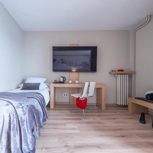 a bedroom with a single bed a desk and a flat screen tv