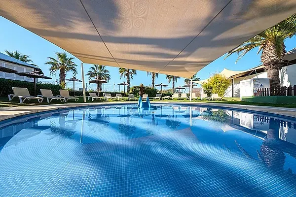 ein großer Swimmingpool mit Sonnenschirmen und Stühlen umgeben