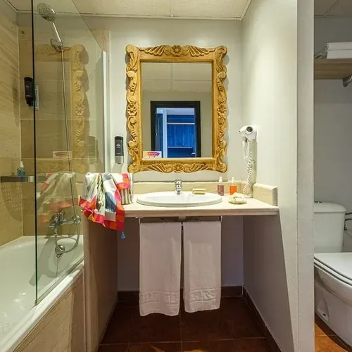 Modern bathroom with tub, sink, and hairdryer at Estival Islantilla 4* | Huelva