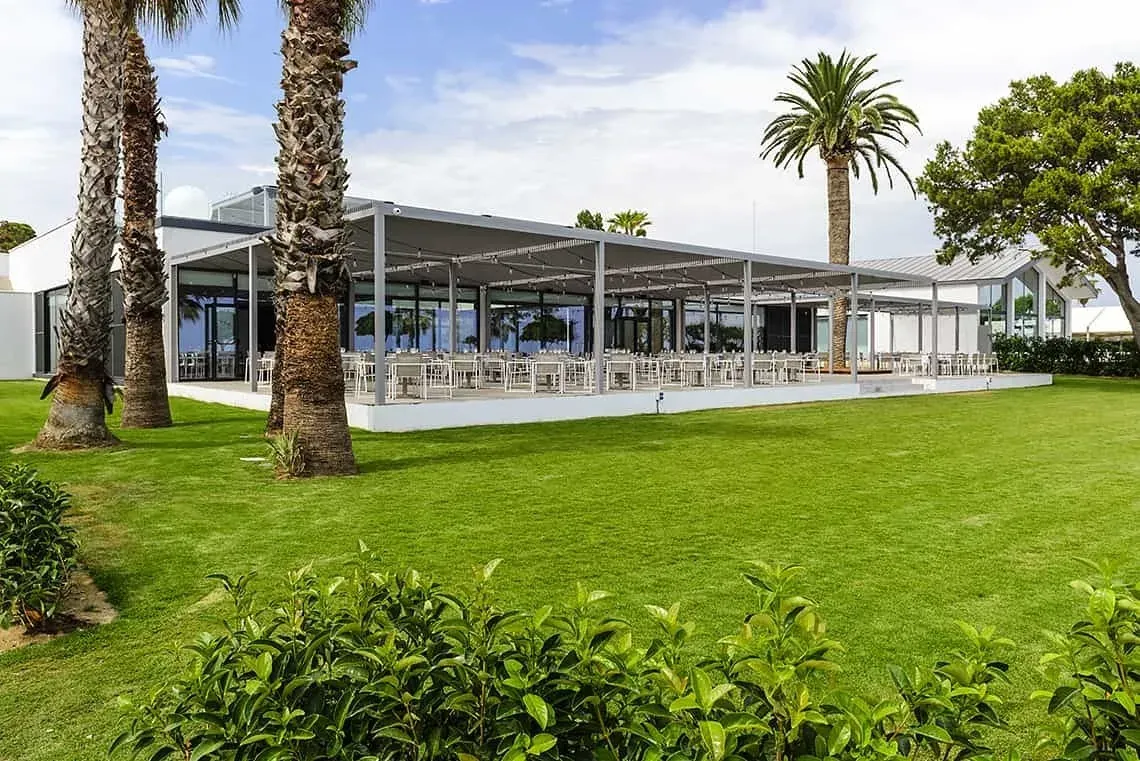 ESTIVAL: Espacio corporativo moderno con mesas al aire libre y palmeras.