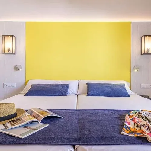 Habitació doble Estival Eldorado Resort amb llit còmode, coixins blaus i decoració vibrant. Reserva al web oficial.