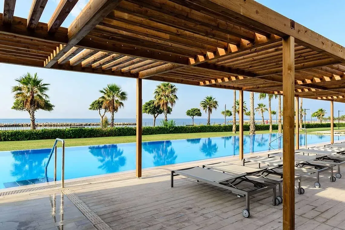 Piscine à débordement avec palmiers et chaises longues. ESTIVAL: Corporatif.