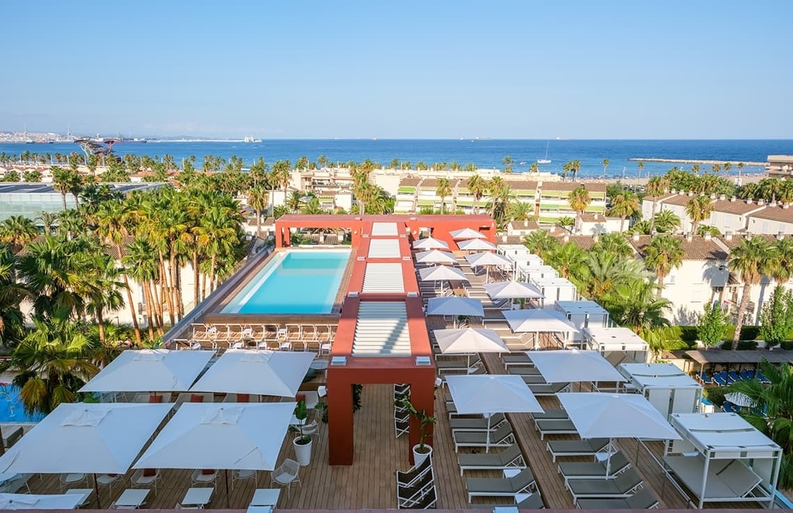una gran piscina rodeada de sillas y sombrillas con vistas al océano