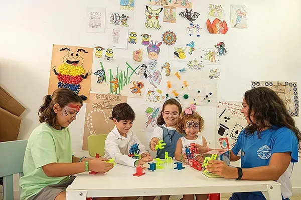 Kinder spielen mit Bausteinen bei ESTIVAL: Corporativa, umgeben von Zeichnungen.