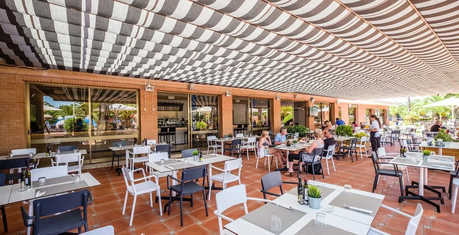 Terraza de restaurante con mesas y sillas listas para disfrutar de la gastronomía | Estival Vendrell Platja | Estival Group | Web Oficial