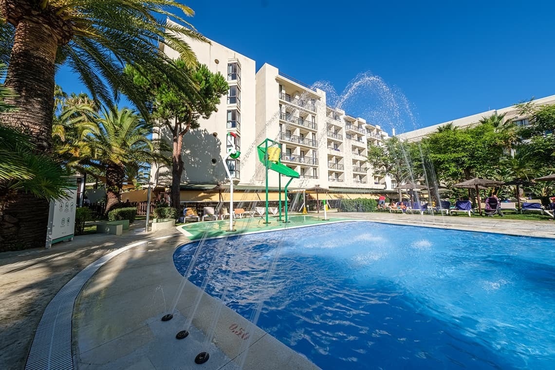 a swimming pool with a fountain in front of a hotel