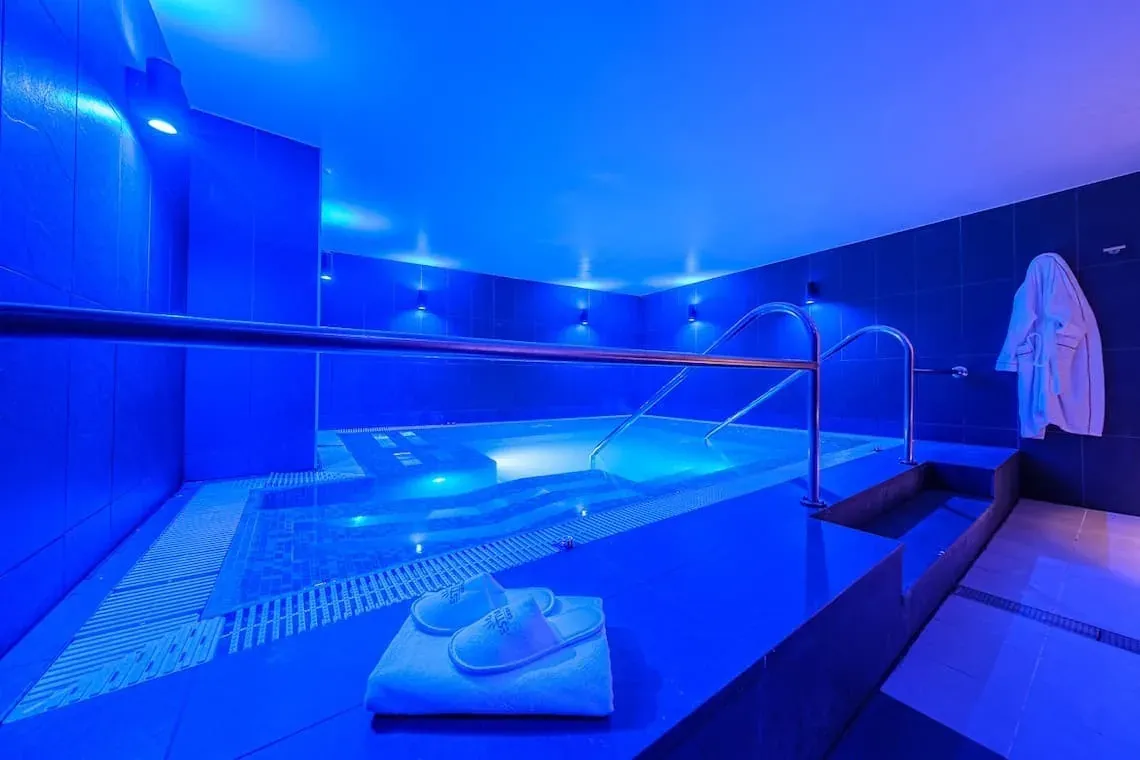 ESTIVAL: Corporate indoor pool with blue lights, robes, and slippers.