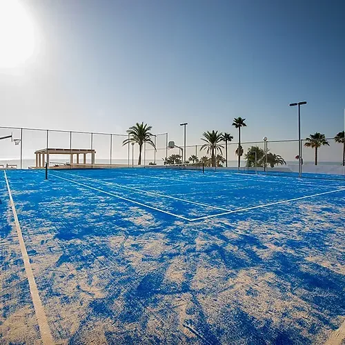 Blue beach tennis court at Estival Torrequebrada Benalmádena with palm trees.