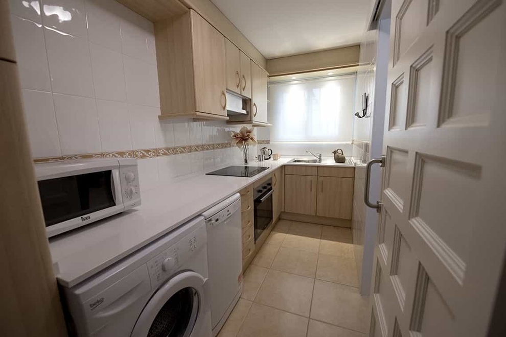 a beko washing machine sits in a kitchen next to a microwave