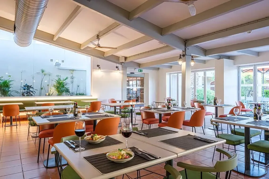 Salle à manger ESTIVAL: Corporatif, tables dressées, chaises orange et lumière naturelle.