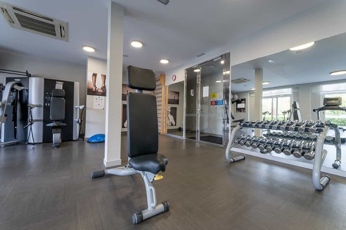 a gym with a bench and dumbbell racks