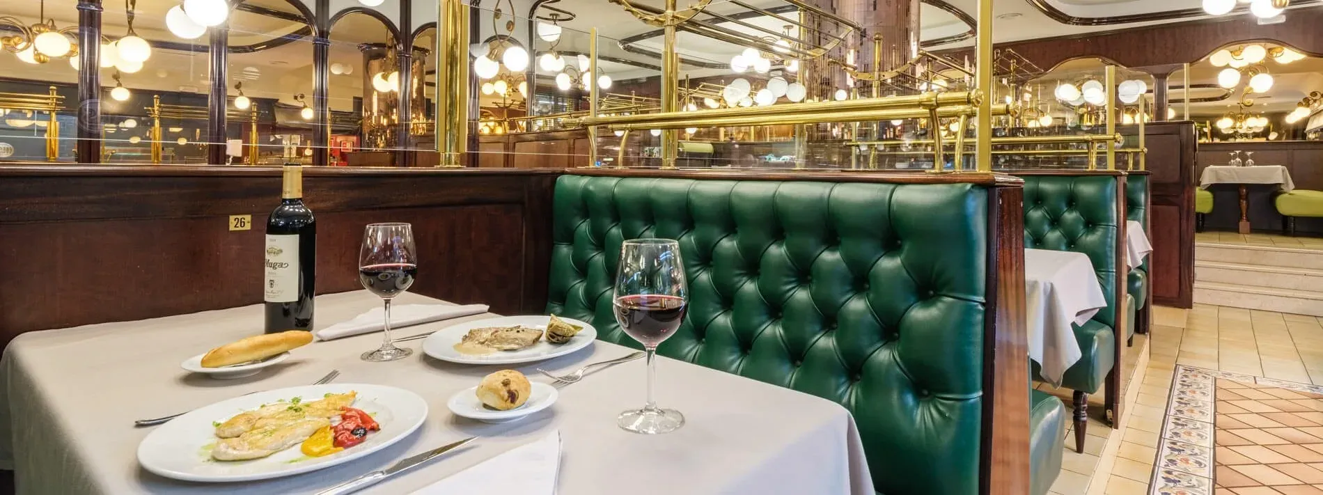 Gastronomia | Hotel Sporting Andorra: taula servida amb vi, peix i pa en entorn clàssic.