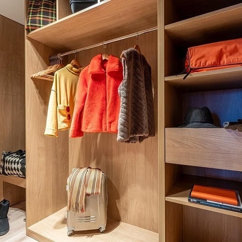 a walk in closet with clothes and a suitcase