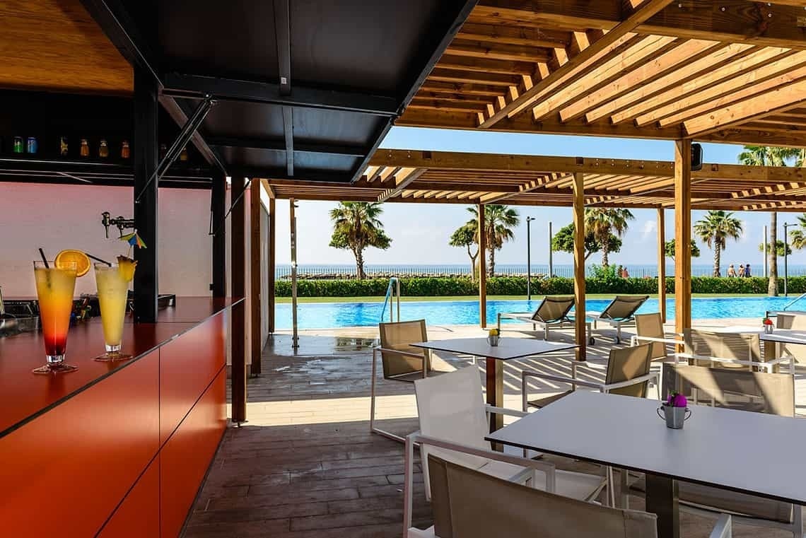 un bar con mesas y sillas junto a una piscina