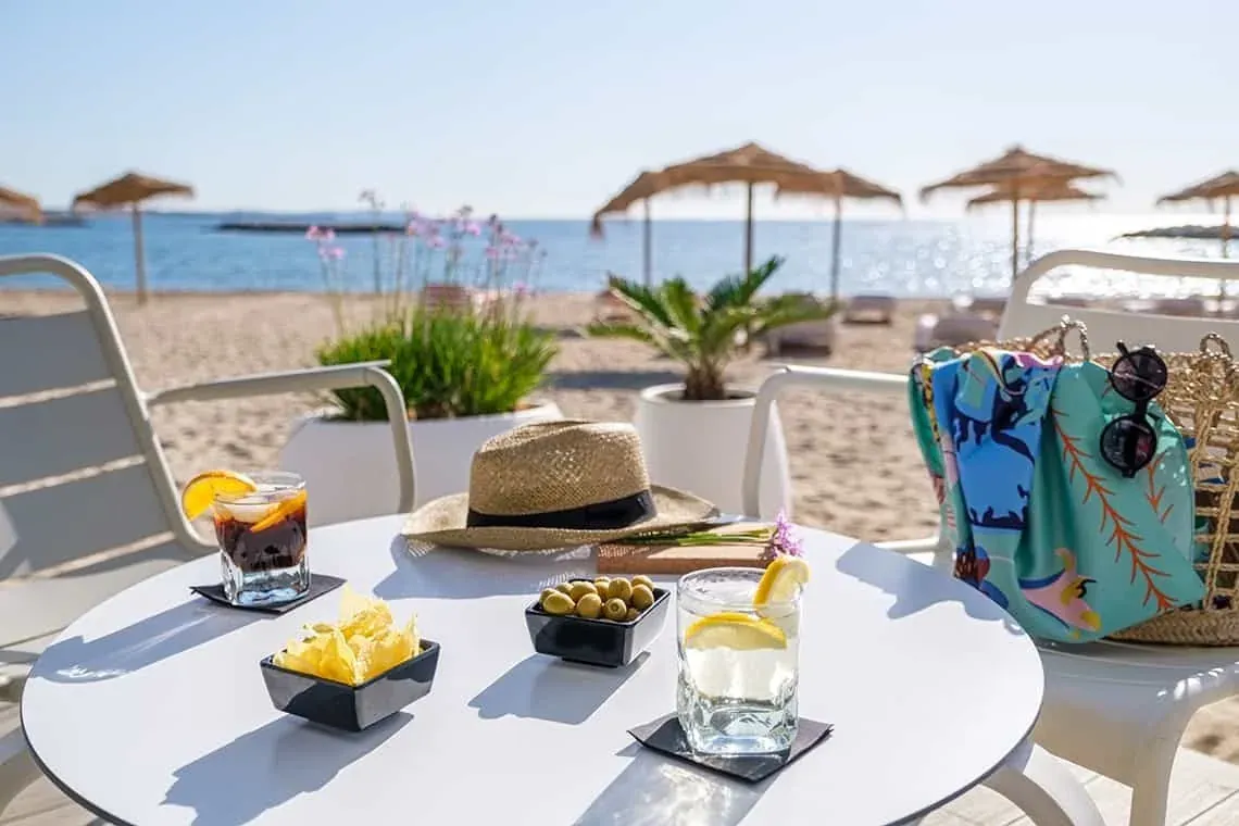 ESTIVAL: Mesa de playa con bebidas, sombrero y patatas.