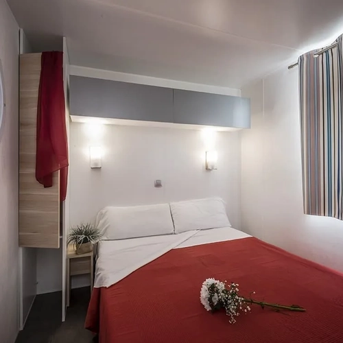Dormitorio acogedor con cama doble, ropa de cama roja y ramo de flores. Estival Vendrell Platja | Baix Penedès, Catalunya | Web Oficial.