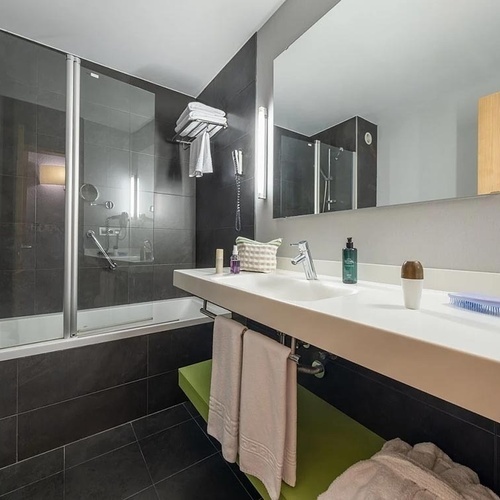 a bathroom with a sink and a bathtub with slippers on the toilet