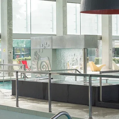 ESTIVAL: Corporate indoor pool with waterfall and lounge chairs.