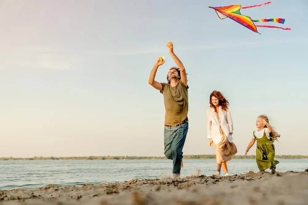 Familia jugando con cometa en la playa, ideal para eventos ESTIVAL: Corporativa.