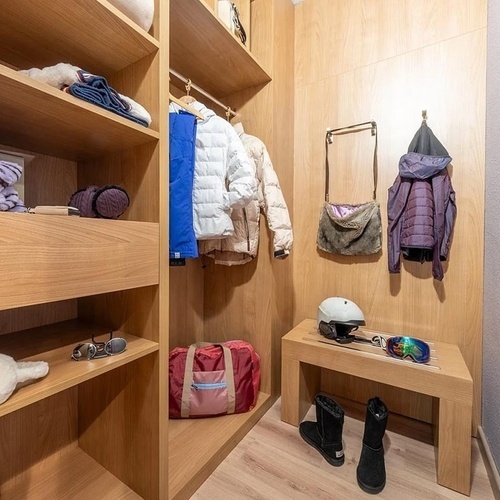 a walk in closet with clothes and a helmet on a bench