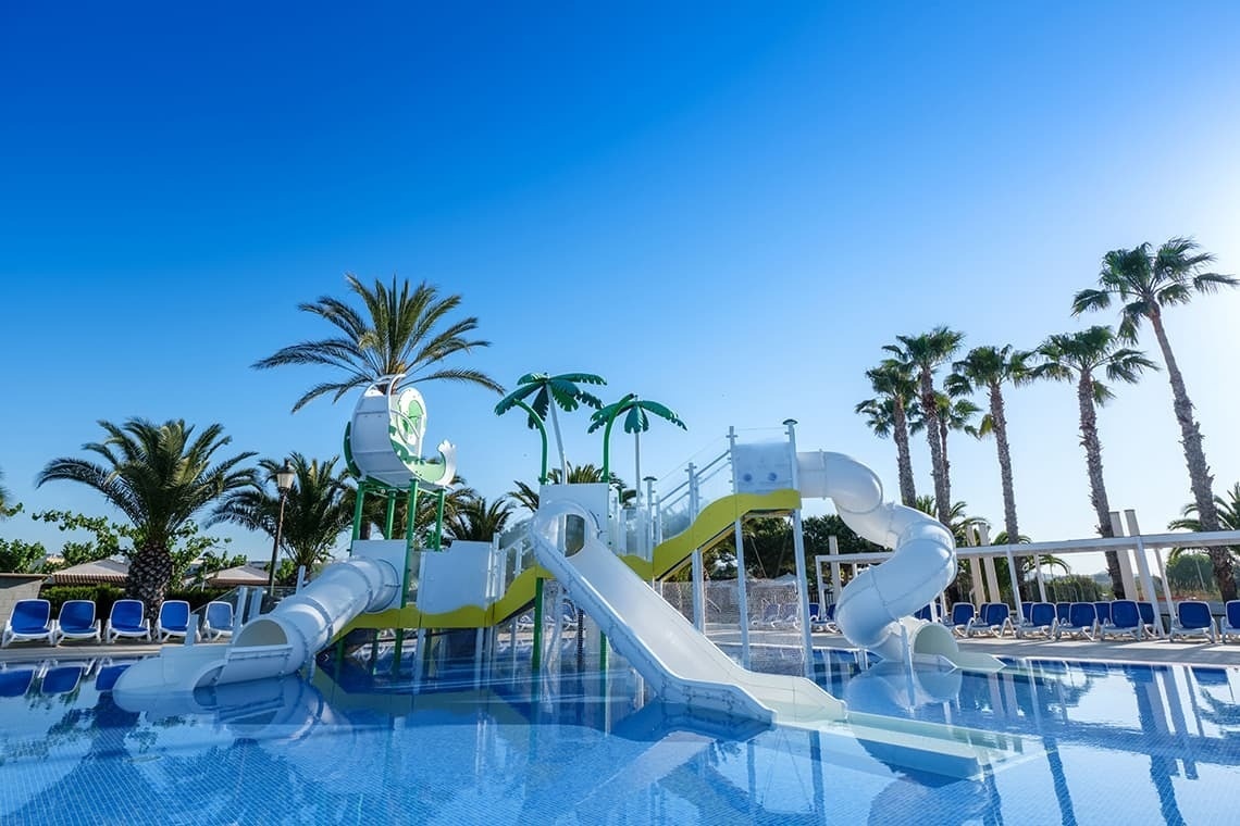 una piscina con toboganes y palmeras en el fondo