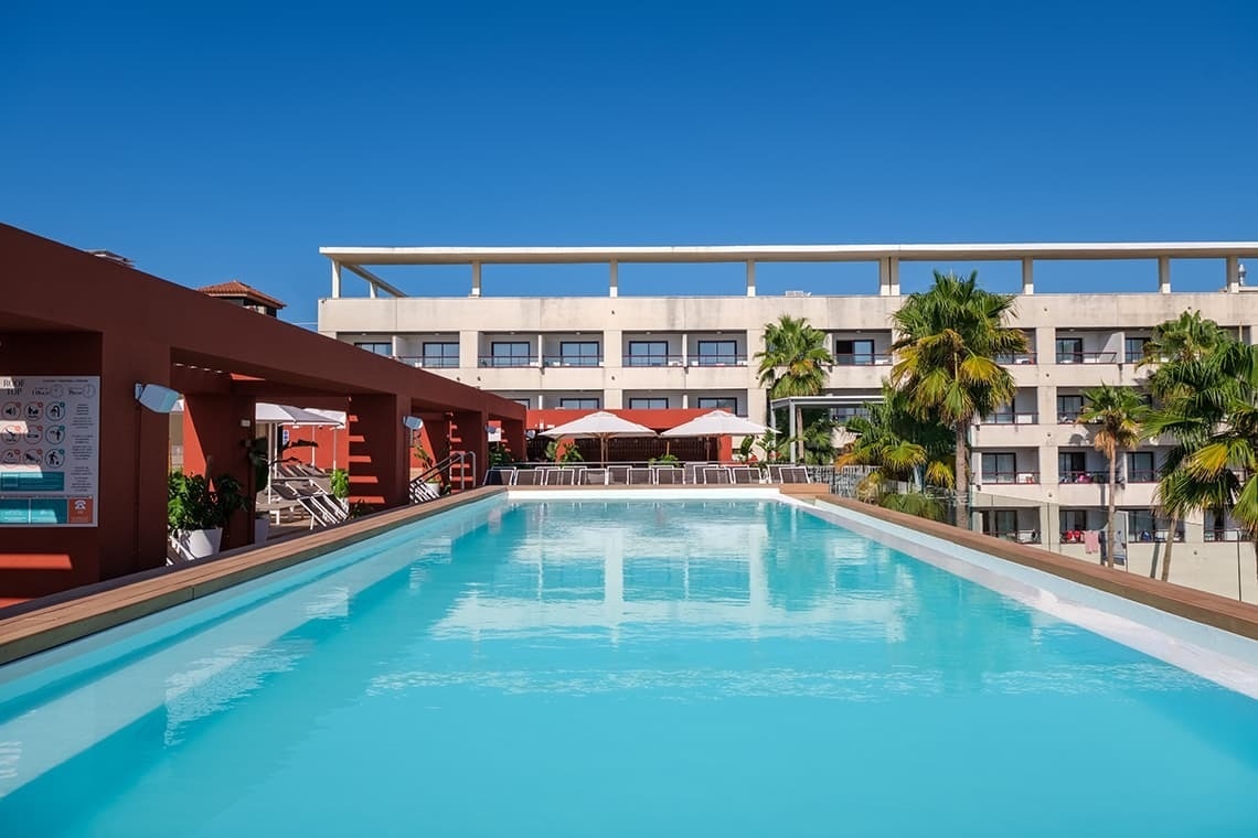 una gran piscina está rodeada de palmeras y edificios