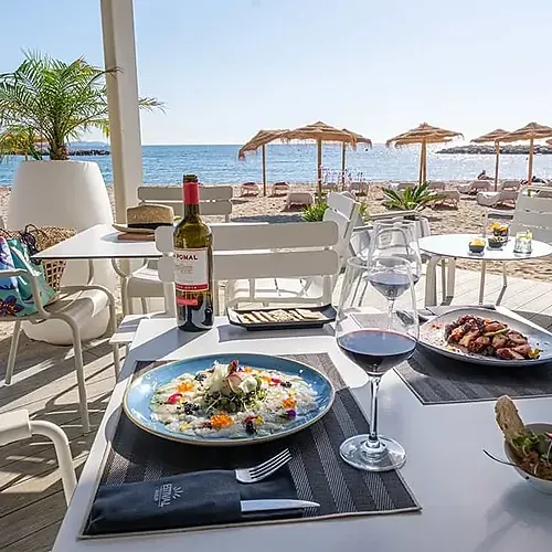 Taula davant del mar al Estival Eldorado Resort | Estival Group | Lloc Web Oficial, amb vi i platillos.