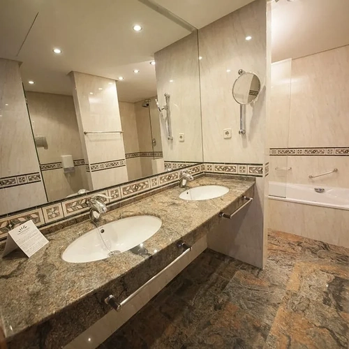 ESTIVAL: Corporate - Bathroom with double vanity, bathtub, and hairdryer.