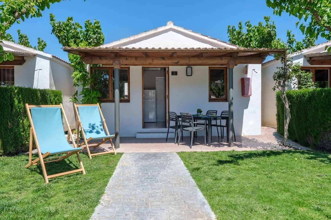 a small white house with lawn chairs in front of it