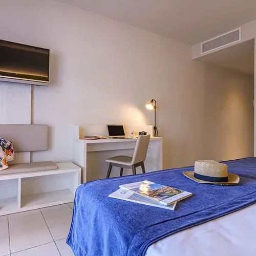 Habitació d'hotel moderna amb llit blau i escriptori Estival Eldorado Resort | Estival Group | Lloc Web Oficial