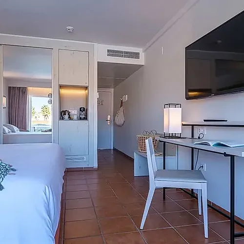 ESTIVAL: Modern room with bed, desk, and flat-screen TV.