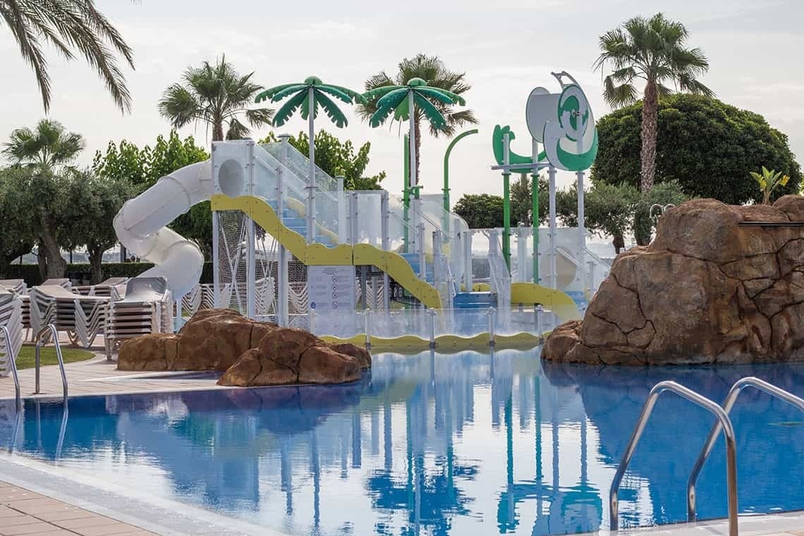 una piscina con un tobogán y palmeras en el fondo