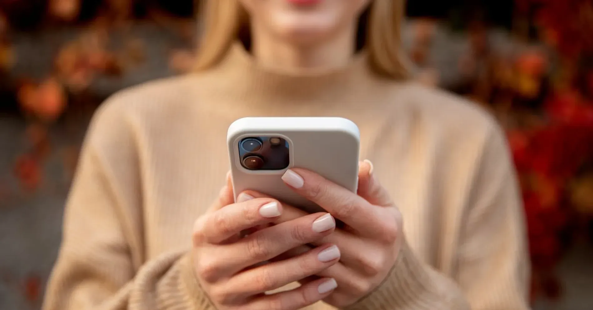 Kontakt zu Ihrer Einrichtung | Estival Group | Offizielle Website: Frau tippt auf Handy im Herbstlaub
