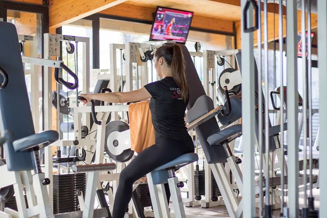 una mujer se sienta en una máquina en un gimnasio