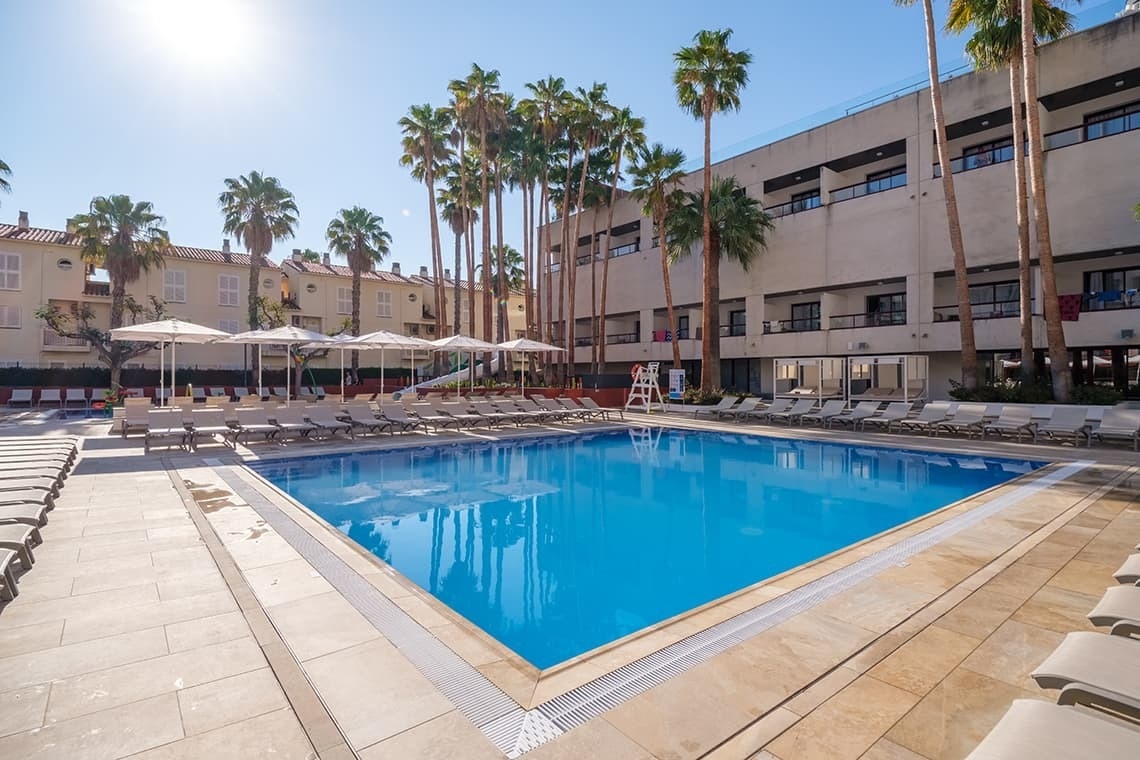 una piscina rodeada de sillas y sombrillas en un hotel