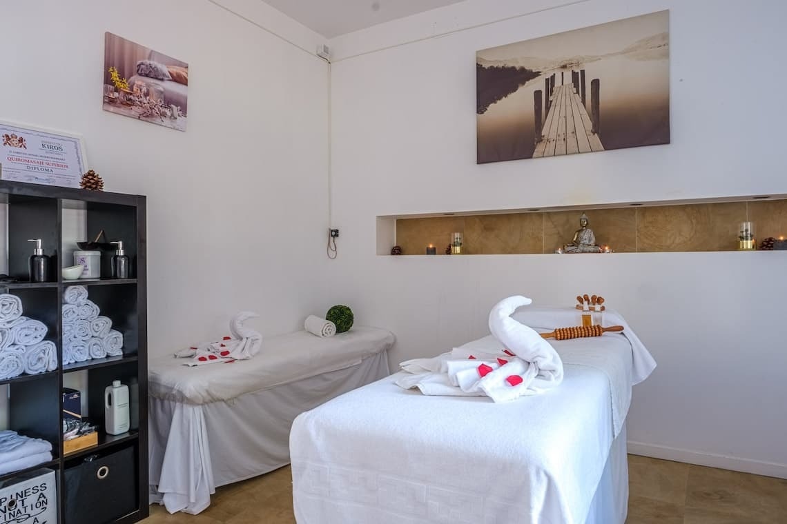 una sala de masajes con dos camas y una estatua de buda en la pared