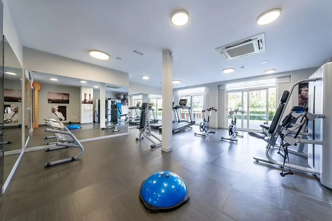Modern ESTIVAL: Corporate gym with machines, weights, and mirrors.