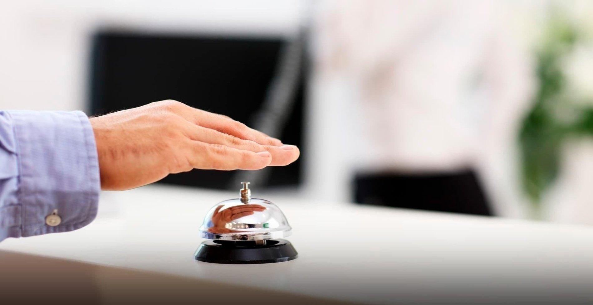 una persona toca una campana de recepció en un hotel