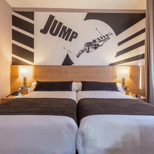 a hotel room with two beds and a painting on the wall that says jump