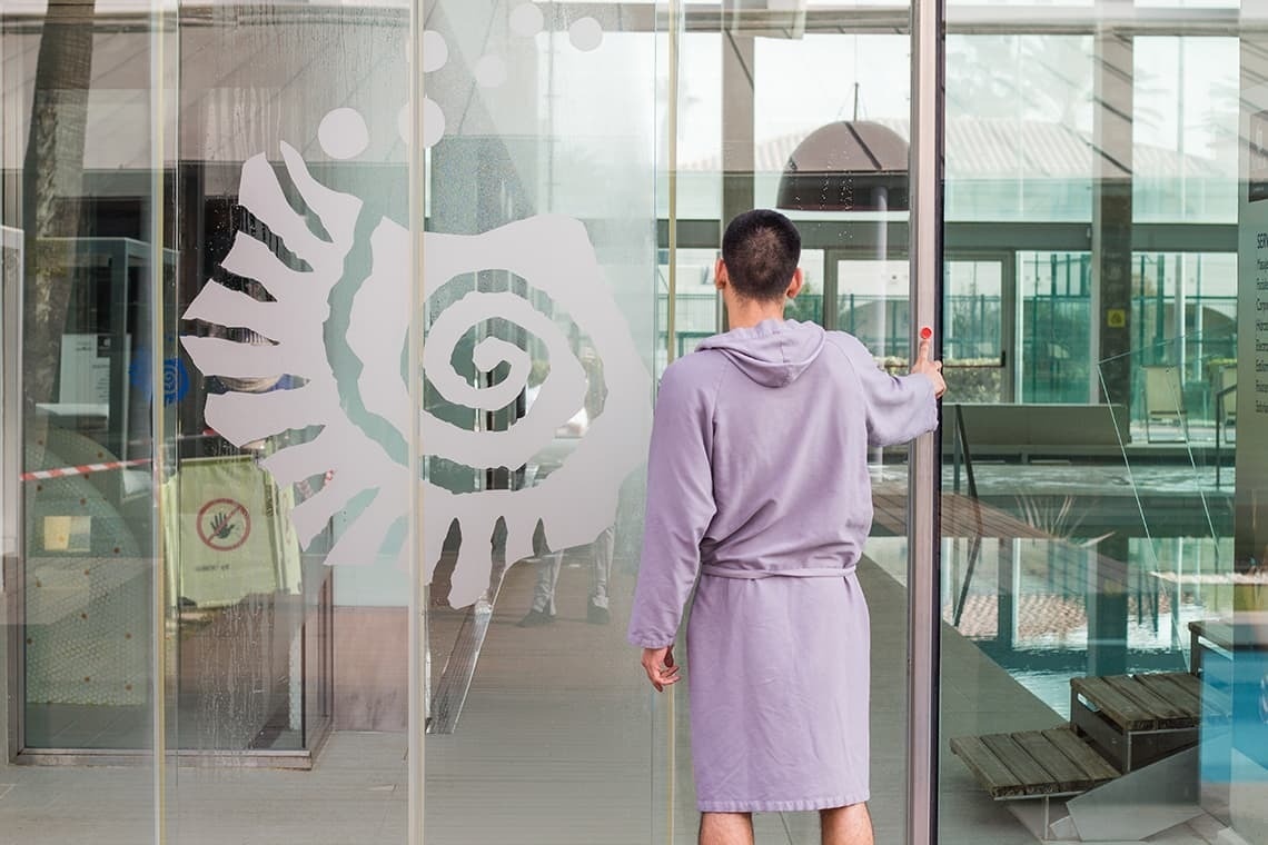 un hombre en una bata abre una puerta de vidrio con un espiral en la pared