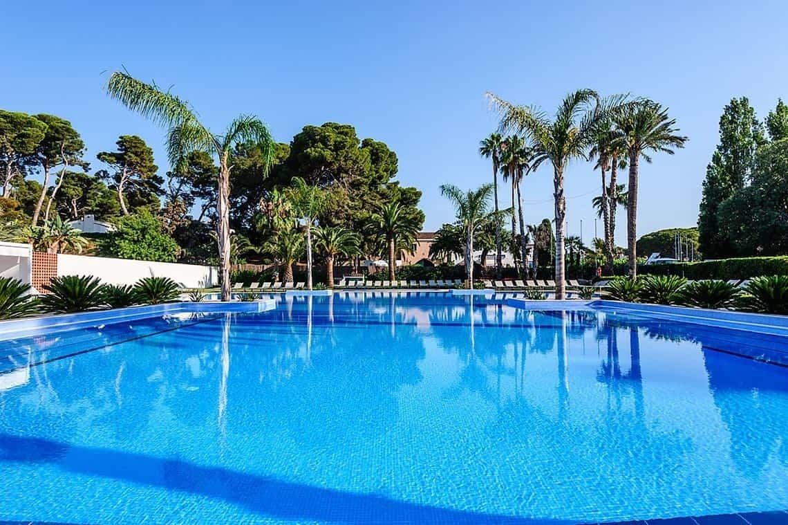 Piscina azul cristalina, palmeras y exuberante vegetación en Estival Eldorado Resort.