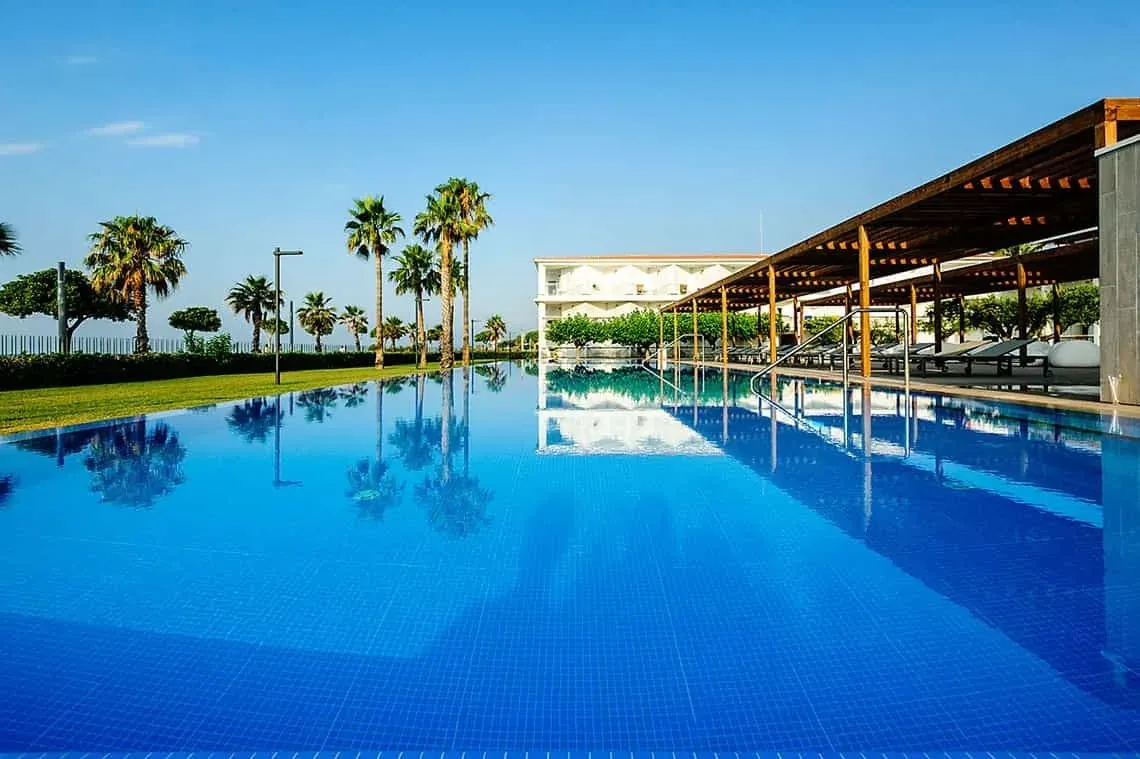 Piscine d'hôtel de luxe, reflets de palmiers et bâtiment. Idéal ESTIVAL: Corporatif.