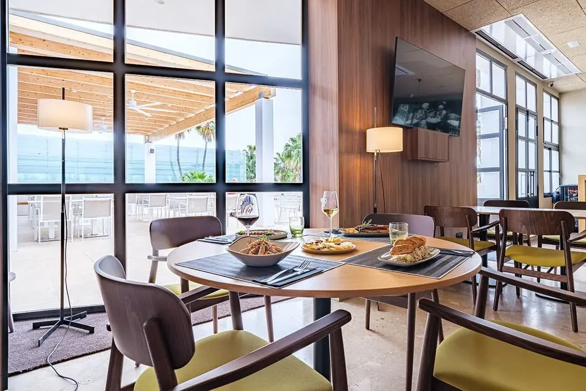 Comedor de ESTIVAL: Corporativa con mesas listas y vistas a la terraza.