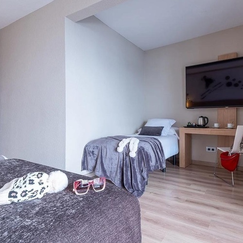 a hotel room with two beds and a flat screen tv