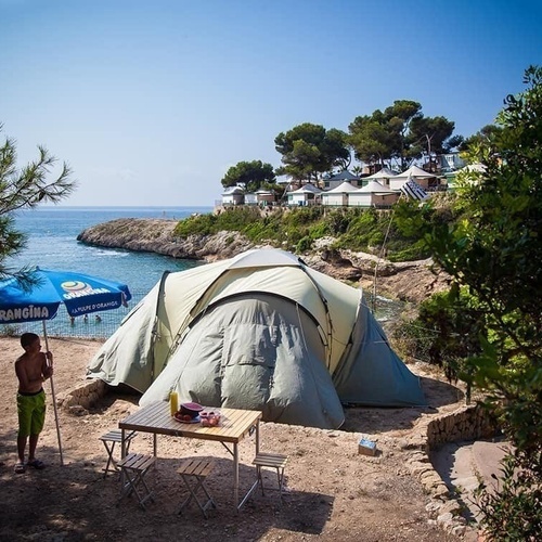 un nen s'acosta a la platja a l' ombresa d' orangina