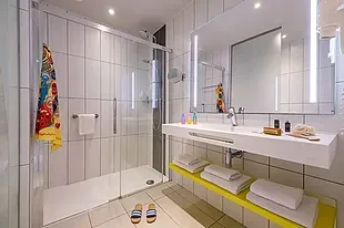 ESTIVAL: Baño moderno con ducha, lavabo y toallas, ideal para estancias corporativas.