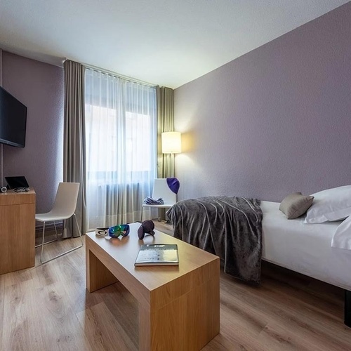 a hotel room with a single bed and a table with a book on it